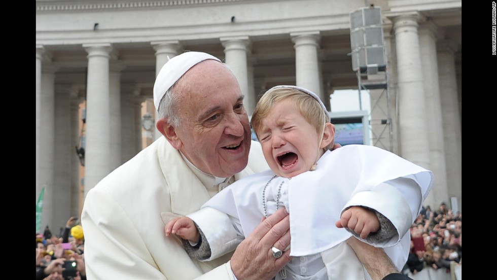 Daniele De Sanctis, a 19-month-old child dressed up as a pope, is handed to Francis as the pontiff is driven through the crowd in St. Peter's Square in February 2014.